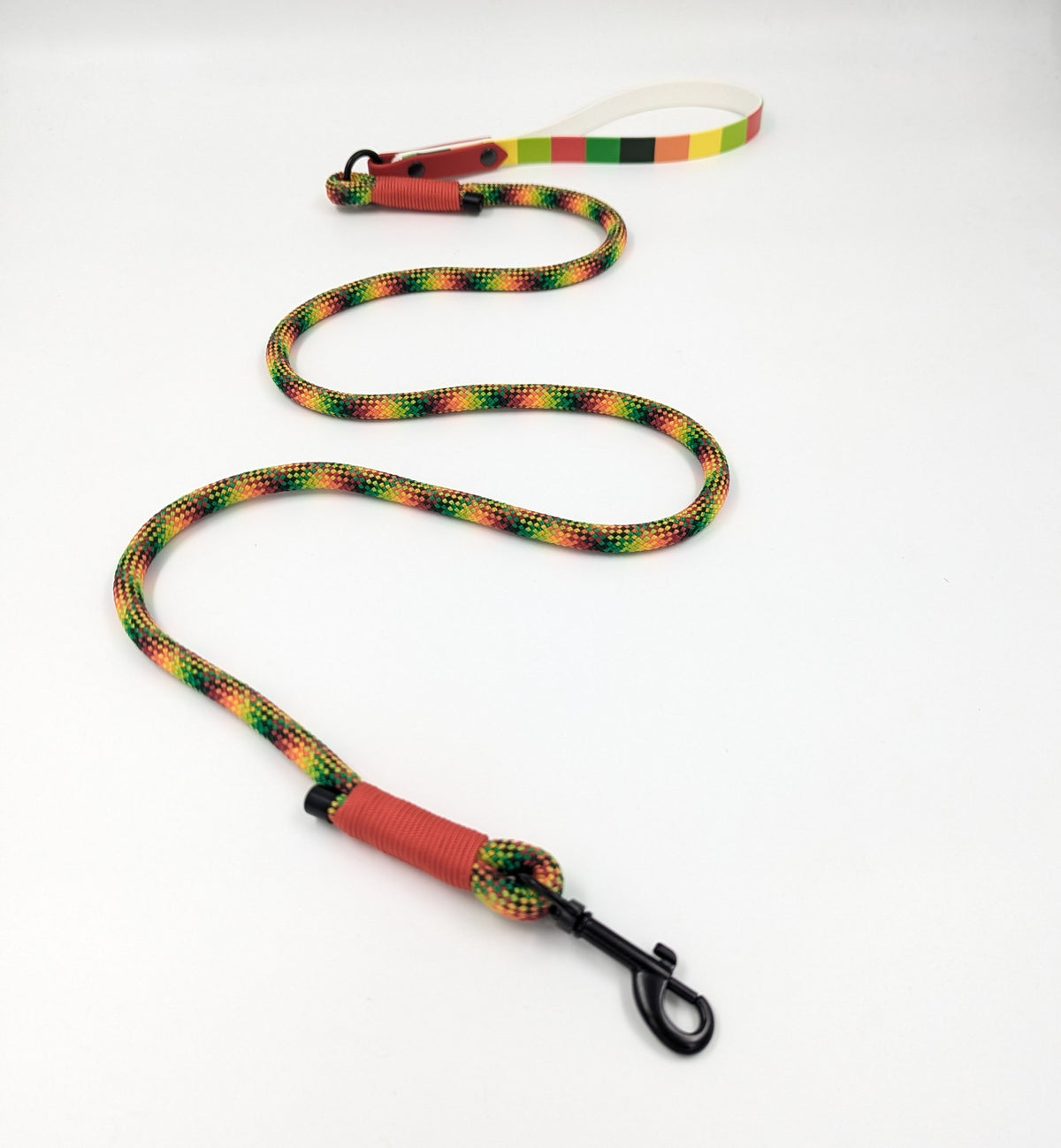A handmade dog leash with a red BioThane and UV printed BioThane handle and a black metal clip, featuring a multicolor pattern of green, yellow, orange, and red BioThane handle at the end. Ireland UK and worldwide.